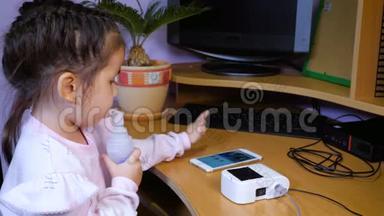 小可爱的女孩接受<strong>雾化</strong>器治疗，并使用手机。
